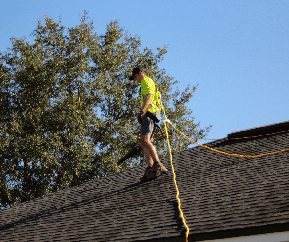 A roofer checking for storm damage on a roof